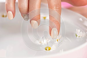 Girls finger nails cream polish touch daisy flower in bowl