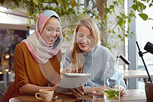 Girls. Friends Meeting In Cafe. Smiling Women Looking At Tablet Screen.