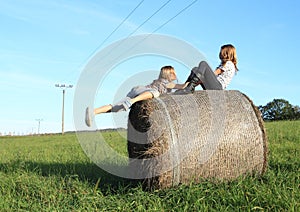 Girls getting up on package of hay