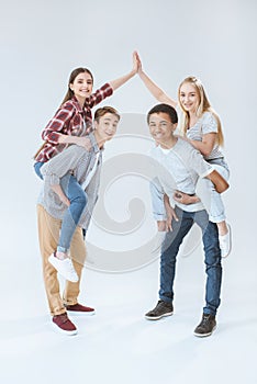girls giving high five while piggybacking with multicultural boys