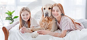 Girls with golden retriever dog in the bed