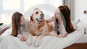 Girls with golden retriever dog in the bed