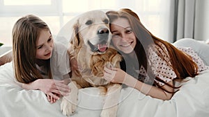 Girls with golden retriever dog in the bed