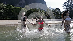 Girls Group Running In Water Holding Hands, Men Standing On Beach In Mountains, Happy Smiling Woman Tourists