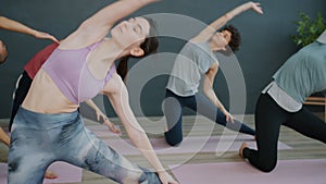 Girls and guy practising yoga stretching body then relaxing in meditative position