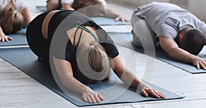 Girls and guys yoga lovers gathered together performing Child Pose