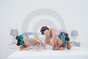 Girls in hair rollers having fun in bed