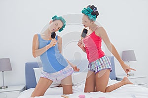 Girls in hair rollers singing with hairbrush