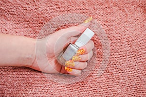 Girls hand with nailart on sweater  and a Bottle of nail polish