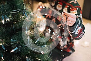 Girls hand putting Christmas lights to tree