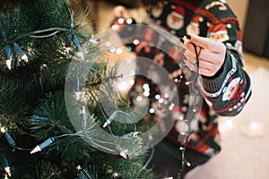 Girls hand putting Christmas lights to tree photo