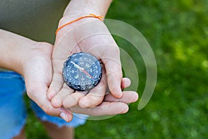 Girls hands holding the compass. Hands of a teenager girl holding a liquid compass. Red compass needle points north