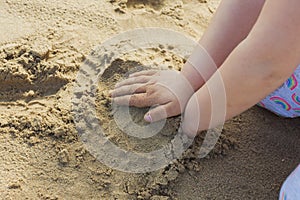 Girls hands playing in the sand at the beach.