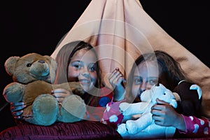 Girls with happy faces playing with teddies in tent