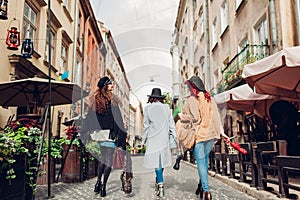 Girls having fun. Outdoor shot of three young women walking on city street. Back view