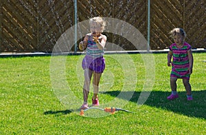 Girls having fun with sprinkler in garden