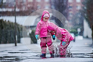 Girls are having fun in water on street in cold autumn day, girls splashing water in rain, cheerful girls enjoying cold weather