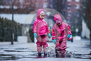 Girls are having fun in water on street in cold autumn day, girls splashing water in rain, cheerful girls enjoying cold weather