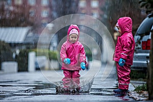 Girls are having fun in water on street in cold autumn day, girls splashing water in rain, cheerful girls enjoying cold weather