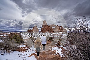 Girls hiking in the snow covered red mountains in Utah.
