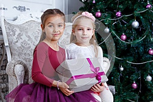 Girls holding big gift-box under Christmas tree