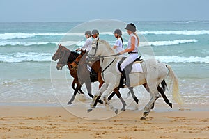 Girls and horses on beach ride