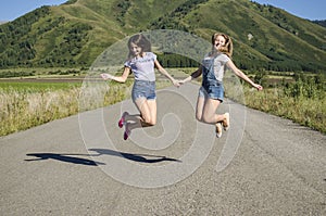 The girls jump on the road holding hands