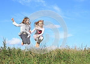 Girls jumping in grass