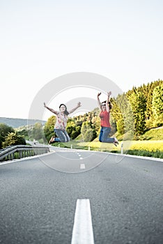 Girls jumping in the middle of road. Friendship