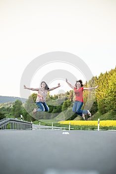 Girls jumping in the middle of road. Friendship