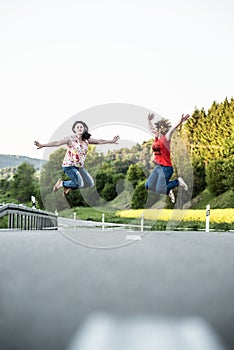 Girls jumping in the middle of road. Friendship