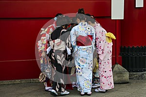 Girls in kimano dresses stand near the wall  in Senso-ji Temple Asakusa area, Tokyo, Japan