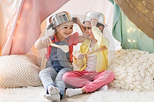 Girls with kitchenware playing in tent at home