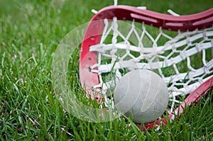 Girls lacrosse head and grey ball on grass