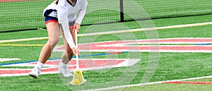 Girls lacrosse player scooping up the ball during a game