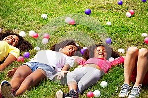 Girls lay in the grass and with color balls around