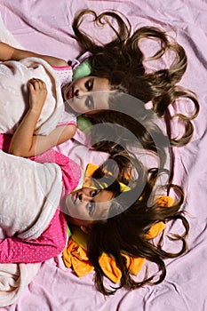 Girls lie on white and pink bed sheets