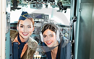 Girls looking at camera. Happy and successful flight. Back view from the inside of the plane. Women pilots smile and