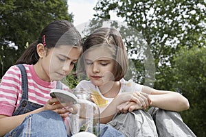 Girls Looking Into Jar Of Insects Outdoors