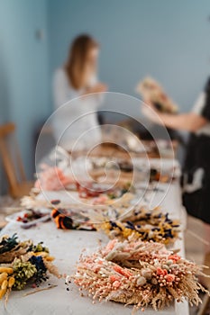 Girls making floral door wreath from colorful dry summer flowers and plants.