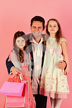 Girls and man with smiling faces hug and hold bags