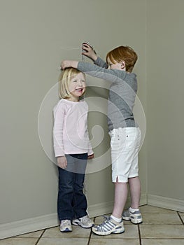 Girls Measuring Height Difference Against Wall