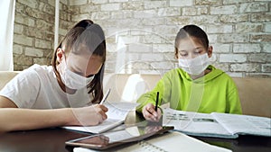 Girls in medical masks studying at home during coronavirus pandemic