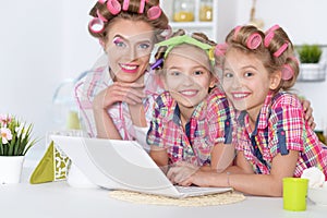 Girls and mother in hair curlers with laptop