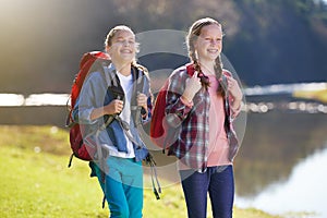 Girls, nature and backpack for walk, river and exercise for outdoor travel holiday. Fitness, smile or hobby for excited