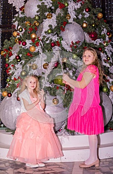 girls near the Christmas tree in the New Year. Holiday. New Year. Children are models. Two sisters.