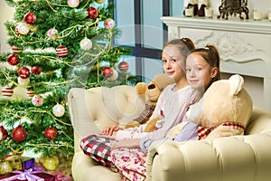 Girls in Pajamas Sitting on Sofa in Front of Decorated Christmas