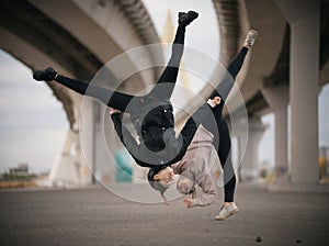 Girls perform splits in the air while jumping on the urban background of the bridge
