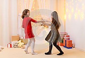 Girls play and dance, home interior decorated with festive lights and gifts