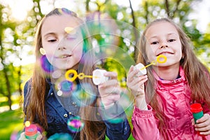 Girls play with soap bubbles in a spring time.